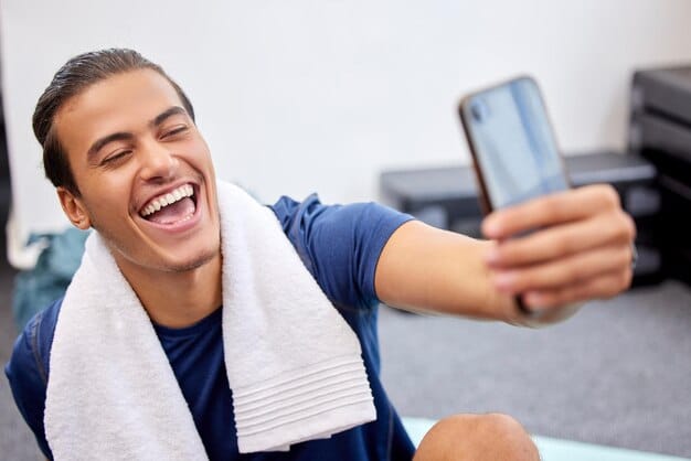 Close-up shot of an athlete posting on social media from the locker room after winning a game. Sincere smile, authentic joy, and engaged interaction with fans in the comments section are visible.
