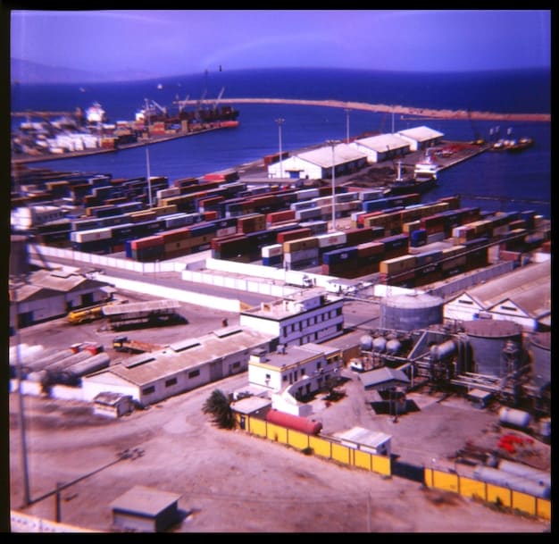 A bustling port with numerous container ships being loaded and unloaded, representing global trade and improved logistics infrastructure.